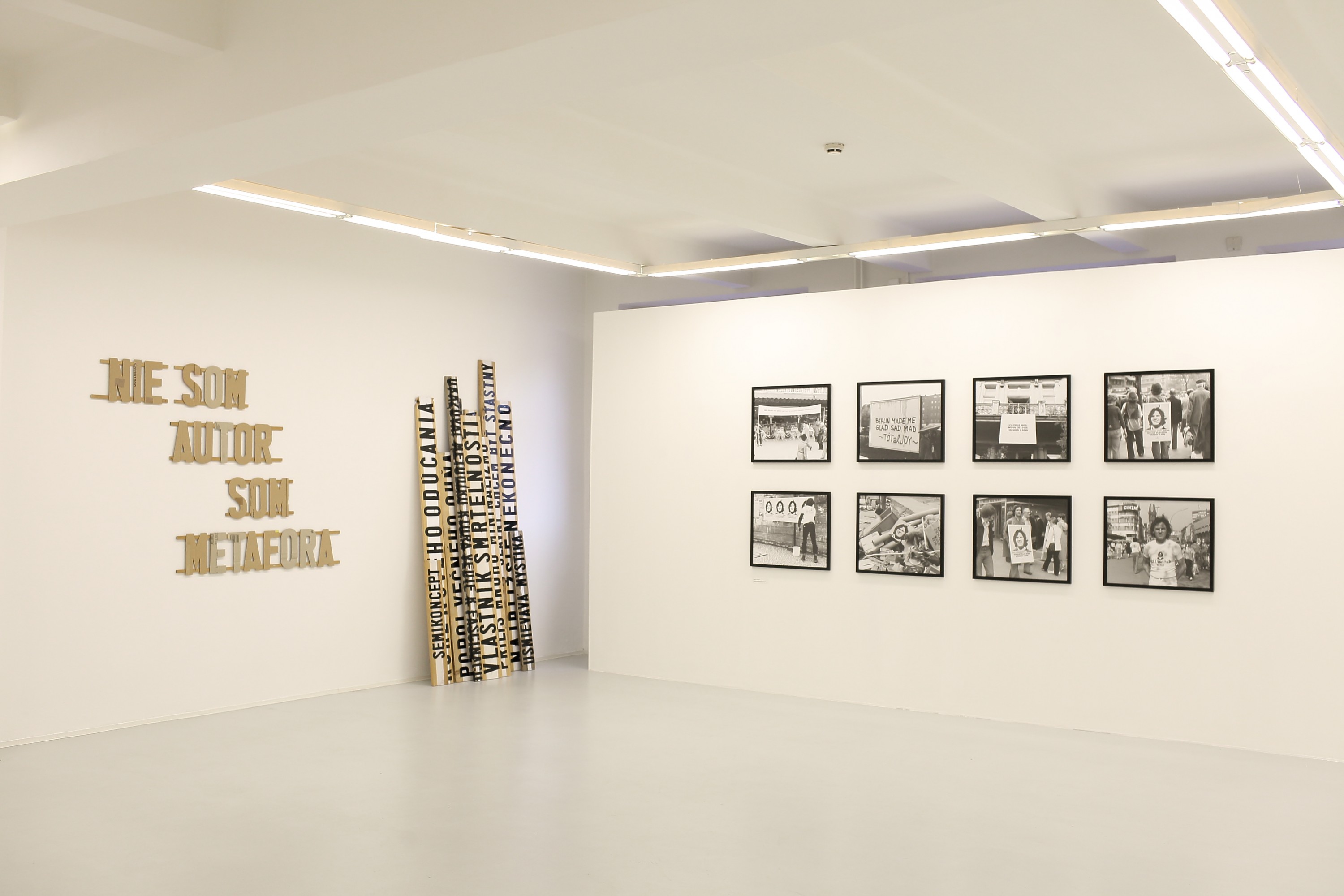 Sala wystawiennicza z wyeksponowanymi na ścianach pracami fotograficznymi oraz instalacją artystyczną.